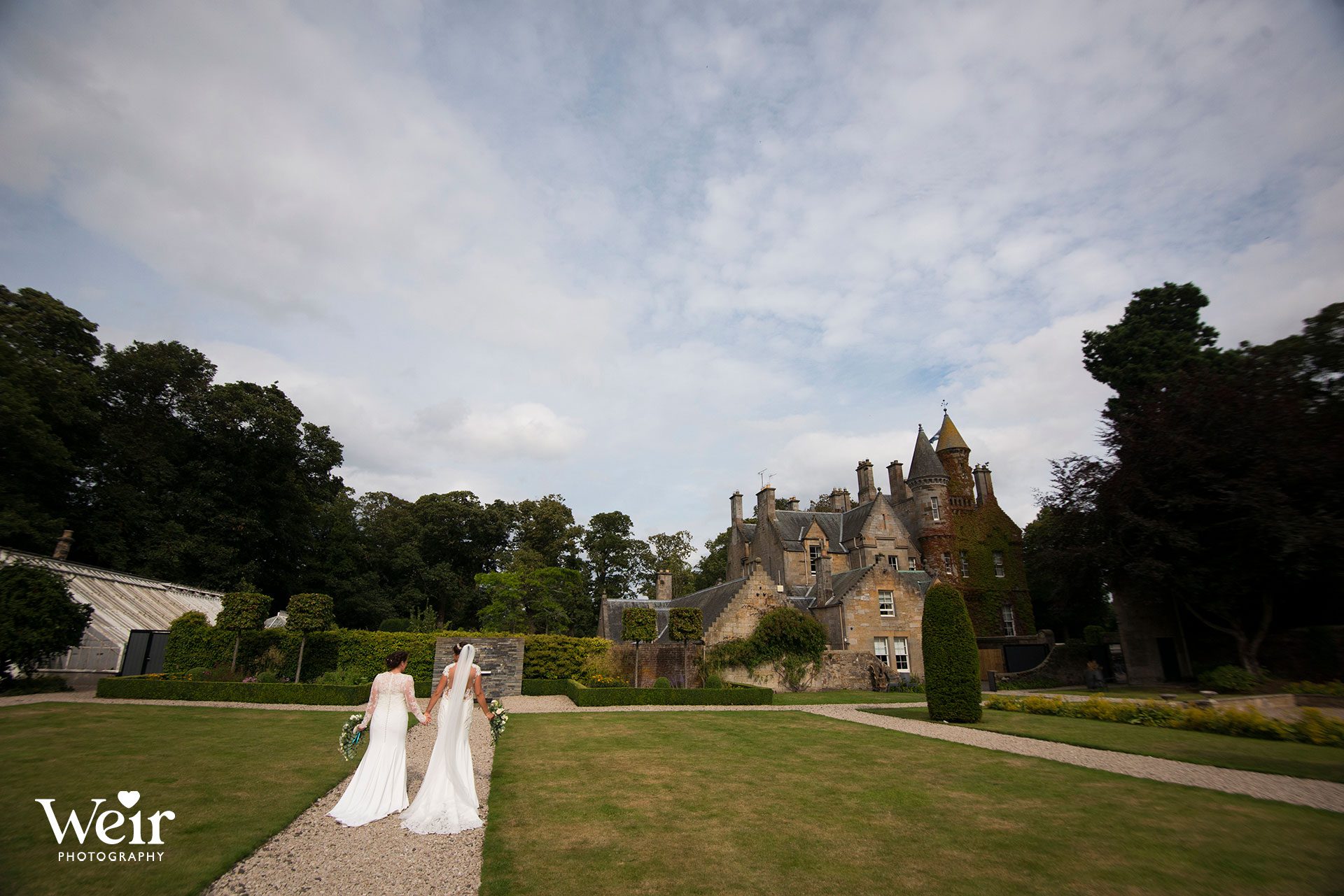 Bride and bride walking in grounds of Carlowrie Castle